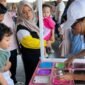 Seorang anak didampingi orang tua mengikuti aktivitas membuat slime berwarna dalam acara slime party interaktif di hotel Surabaya, dengan suasana ramai dan ramah keluarga
