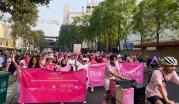 Peserta NCO Pink Morning Club membawa spanduk saat fun walk Pink October di Surabaya.